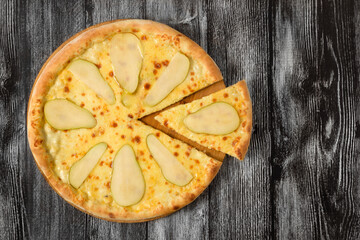 Pizza with pear, shot from above against a dark background with copy space.