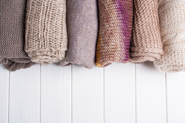 Knitted things on a white wooden background. View from above