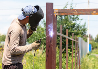 A worker welds metal for a fence.
