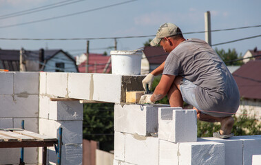 A worker builds the walls of a house from aerated concrete bricks.