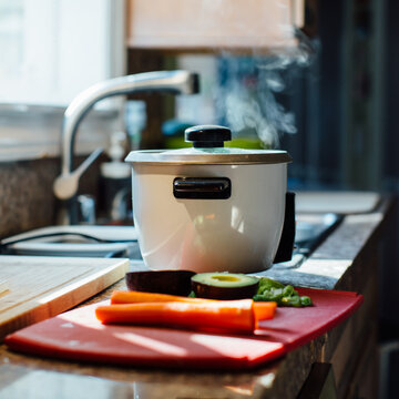 Steaming rice cooker on the counter with ingredients