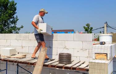 A worker builds the walls of a house from aerated concrete bricks.