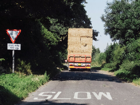 Slow sign and lorry transporting straw bales along a country roa