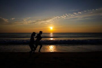 Fototapeta premium Couple jogging on a Black Sea beach during a pleasant late summer sunrise.