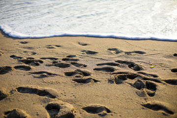 Human footprints on the sand of a beach during a peaceful late summer sunrise.