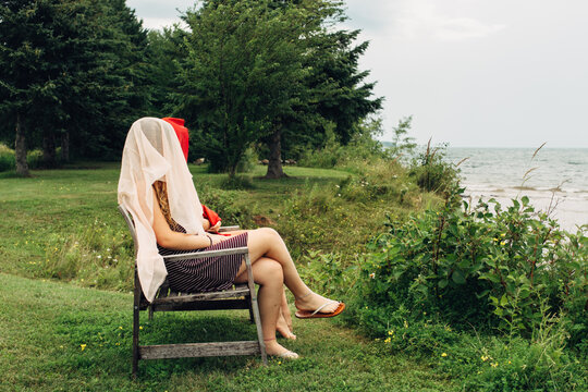 Two teenage girls sitting on a bench by a lake with heads covere