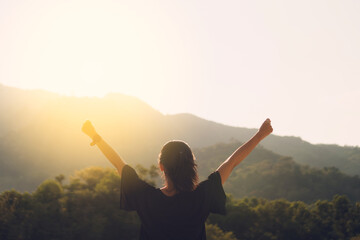 Copy space of woman rise hand up on top of mountain and sunset sky abstract background.