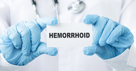Doctor holding a tablet pc with hemorrhoid sign on blue background
