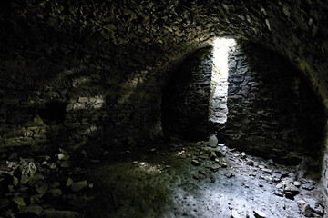 Interior of old castle cellar with dome ceiling and stones on floor
