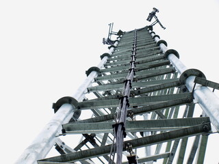 Cable and grounding on the tower. Installed on a 3G, 4G, and 5G wireless telecommunication base structure on a metal background and white sky. Selective focus