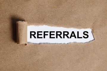 referrals. text on white paper on torn craft paper