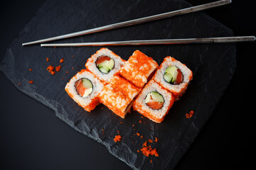 sushi with chopsticks on black plate