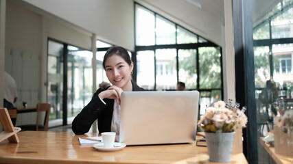 Attractive young businesswoman sitting on her workplace and looking at camera.