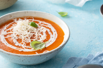 Pumpkin and carrot soup with cream on blue stone background.