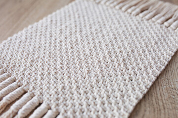Fototapeta na wymiar Handmade beige macrame pattern background. Macrame texture, ECO friendly, modern knitting. Macrame rug on wooden table