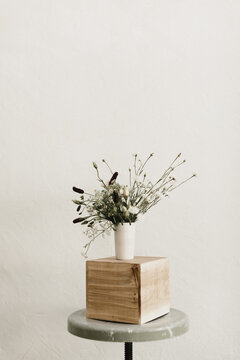 white vase of plants on wooden block