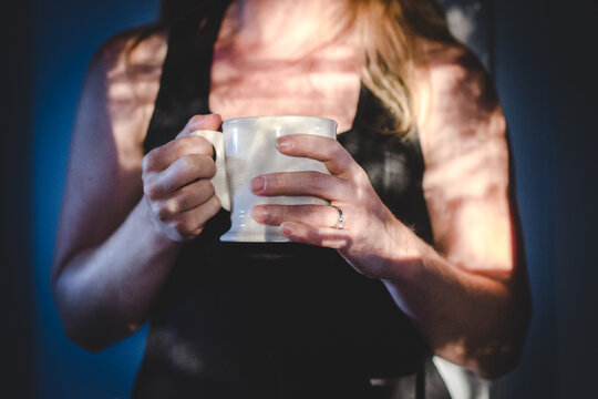 Woman holding morning coffee in sunlight