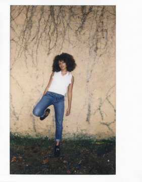 brunette with afro posing on wall with branches