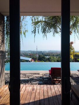 Windows views of a infinite pool and city from inside of a house