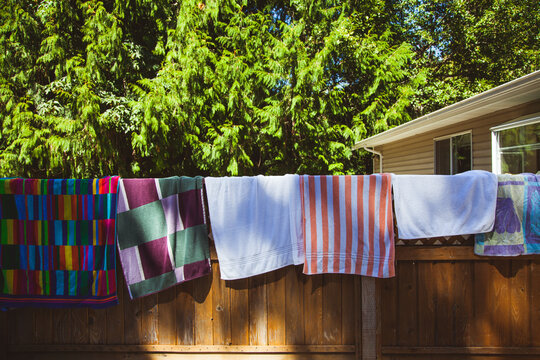 Colourful towels air dry on a fence in the summer sun.