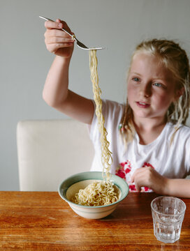 A little girl eating instant noodles.