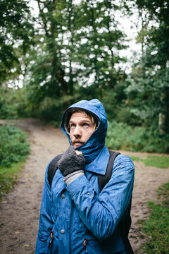 Young man looking up and disliking the weather in the forest