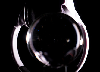 White headphones playing with their reflection in a crystal ball on a black background with different lighting. Audio concept