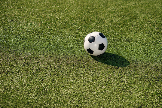 A classic black and white soccer ball lies on artificial grass at soccer field. Sports and healthy lifestyle concept.