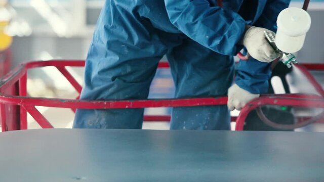 Worker Painting steel construction with Spray Pistol wearing mask, close up, blue red and silver