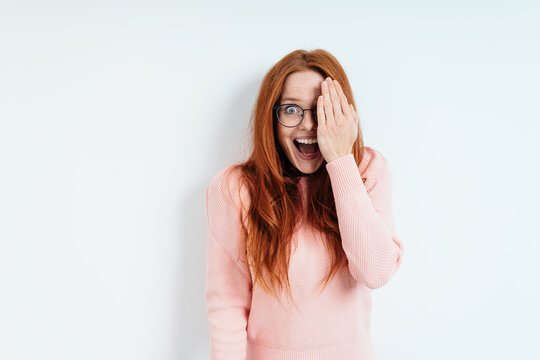 Laughing excited young woman covering one eye