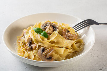 Homemade egg pasta tagliatelle with mushrooms and cheese, close up, white background.