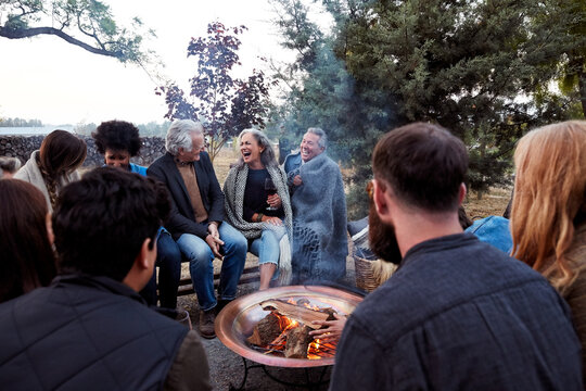 Group of friends and family relaxing around a fire pit at a farm