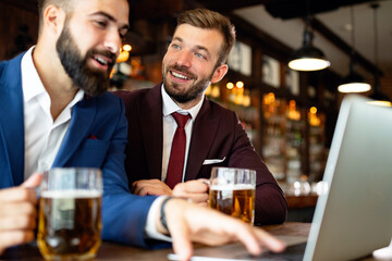 Meeting with the best friends. Happy young business men talking and drinking beer in a pub