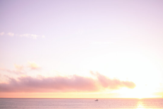 A boat cruising on the open ocean at sunset.