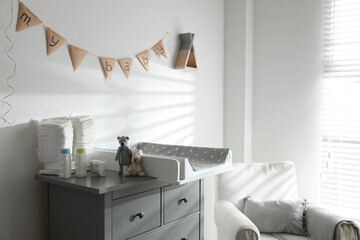 Chest of drawers with changing tray and pad in baby room. Interior design