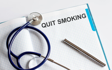 Paper with text QUIT SMOKING on a table with stethoscope