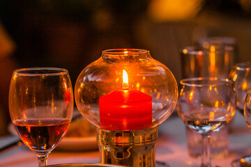 Candle stick in a glass bubble with glass of wine on the side