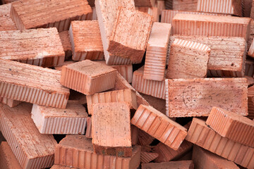 Obraz na płótnie Canvas Red bricks piled in a heap. Background. Construction concept, building materials.