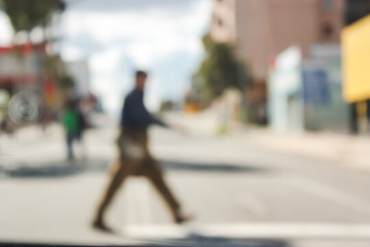 Defocused image of man striding across a city street