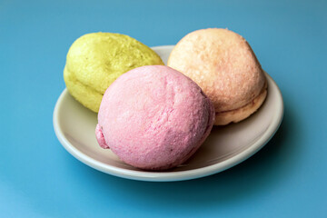 Multicolored macarons on a white plate, on a blue background
