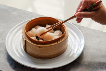 Asian steamed dish. Dim sum on a food shelves, various Chinese steamed dumpling in bamboo basket steamer in Chinese restaurants. with a chopstick