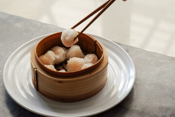 Asian steamed dish. Dim sum on a food shelves, various Chinese steamed dumpling in bamboo basket steamer in Chinese restaurants. with a chopstick