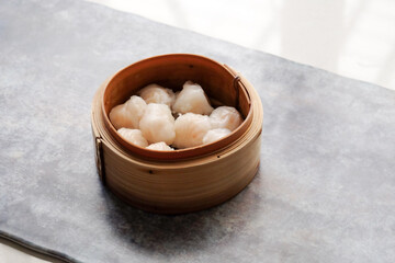 Asian steamed dish. Dim sum on a food shelves, various Chinese steamed dumpling in bamboo basket steamer in Chinese restaurants. with a chopstick