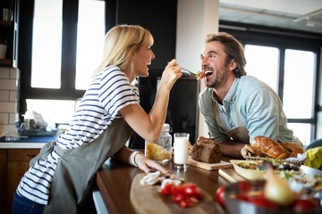 Portrait of happy young couple cooking together in the kitchen at home.