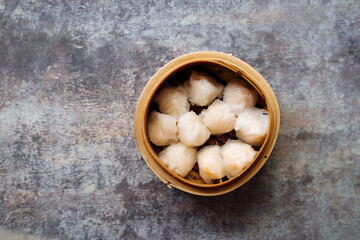 Asian steamed dish. Dim sum on a food shelves, various Chinese steamed dumpling in bamboo basket steamer in Chinese restaurants. with a chopstick