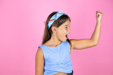 Young beautiful child girl over isolated pink background showing arms muscles smiling proud