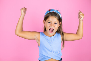 Young beautiful child girl over isolated pink background showing arms muscles smiling proud