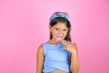 Young beautiful child girl over isolated pink background disgusted with her hand inside her mouth