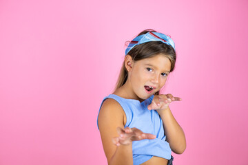 Obraz na płótnie Canvas Young beautiful child girl over isolated pink background smiling funny doing claw gesture as cat, aggressive expression