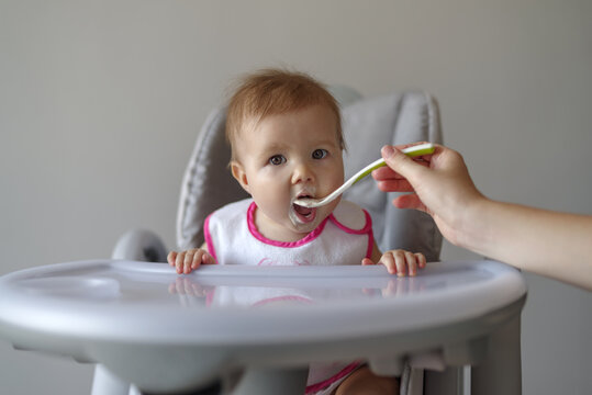 Baby Girl In High Chair Eating Her Baby Food